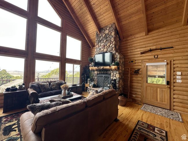 Living area featuring high vaulted ceiling, a stone fireplace, wood ceiling, log walls, and beam ceiling | Image 5