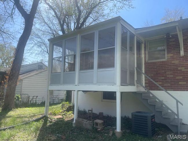 Rear view of property featuring brick siding, a sunroom, stairs, and cooling unit | Image 27
