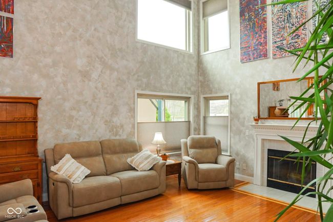 living area with hardwood / wood-style flooring, a high ceiling, and a tile fireplace that's gas or wood burning | Image 14