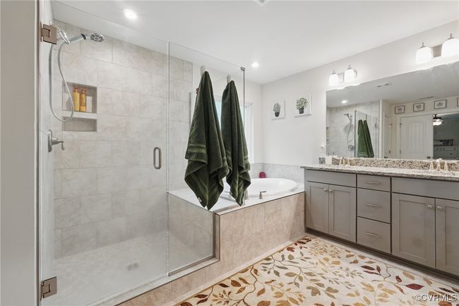 Spa-like ensuite bath with dual vanities, walk-in shower, and soaking tub. | Image 19