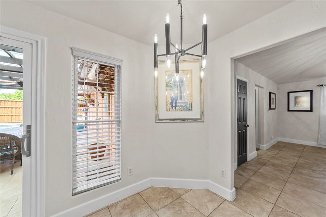 Unfurnished dining area with light tile patterned floors, a notable chandelier, and baseboards | Image 20