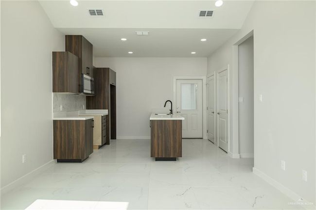 Kitchen with stainless steel microwave, baseboards, modern cabinets, light countertops, and recessed lighting | Image 5