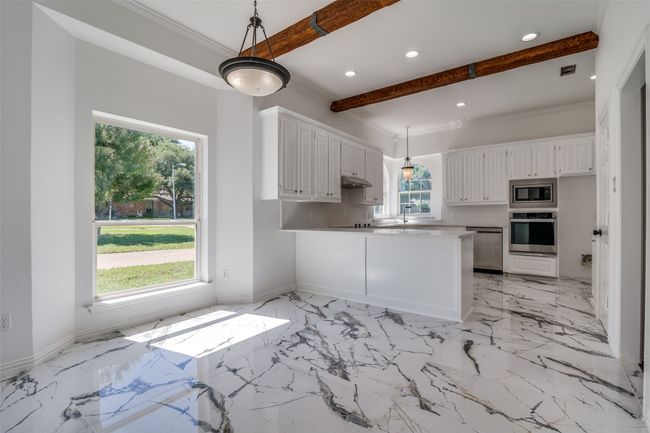 Kitchen featuring appliances with stainless steel finishes, beamed ceiling, a peninsula, white cabinets, and recessed lighting | Image 10
