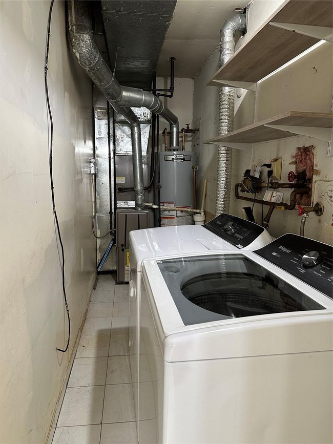 Clothes washing area featuring laundry area, washing machine and dryer, water heater, and light tile patterned floors | Image 13