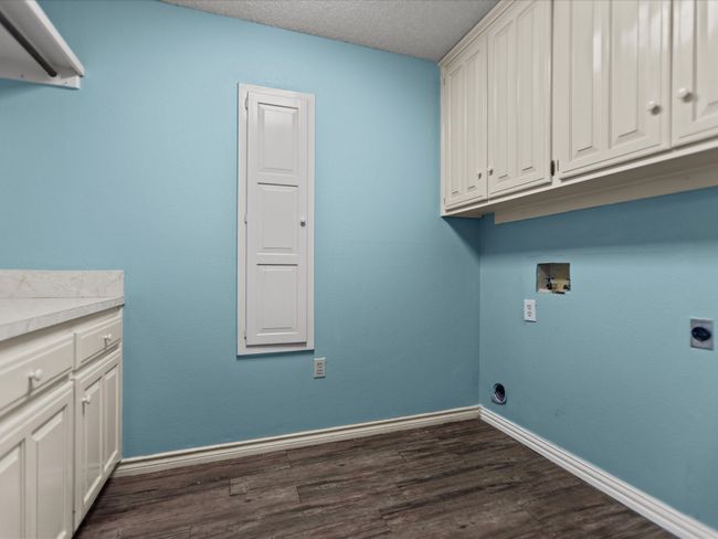 Laundry area with hookup for an electric dryer, dark wood finished floors, cabinet space, hookup for a washing machine, and a textured ceiling | Image 20