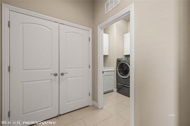 Laundry room featuring visible vents, washer / clothes dryer, light tile patterned floors, baseboards, and cabinet space | Image 49