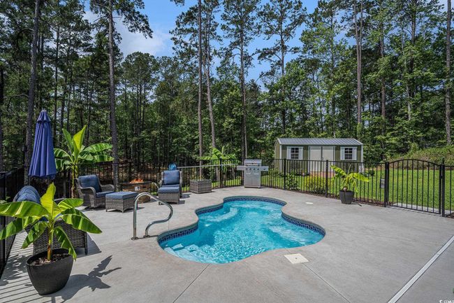 View of swimming pool with a patio area, fence, an outbuilding, and a grill | Image 31