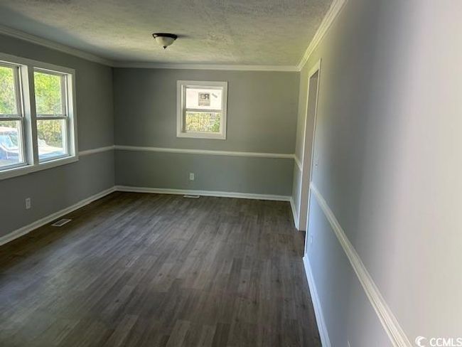 Spare room with a textured ceiling, dark wood-style floors, ornamental molding, and baseboards | Image 10
