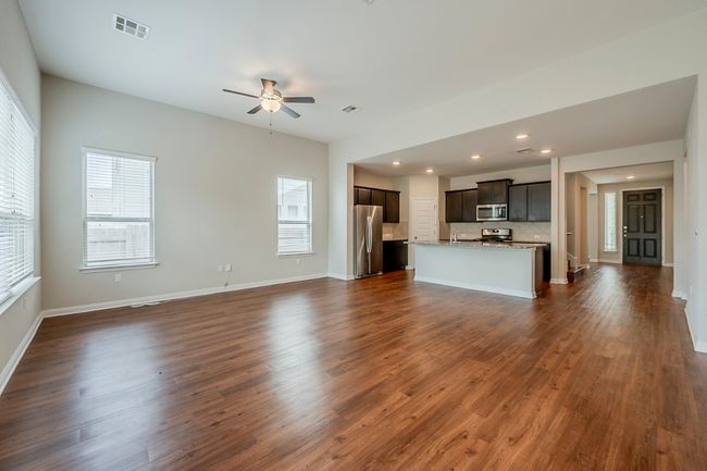 Unfurnished living room featuring a ceiling fan, visible vents, dark wood finished floors, and recessed lighting | Image 10