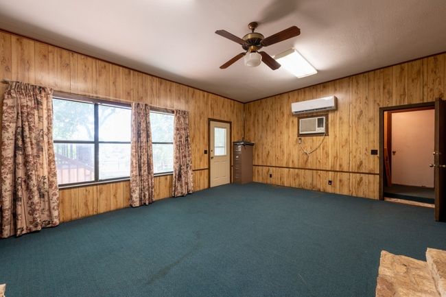 Spare room with an AC wall unit, wood walls, carpet flooring, ceiling fan, and a wall mounted AC | Image 21