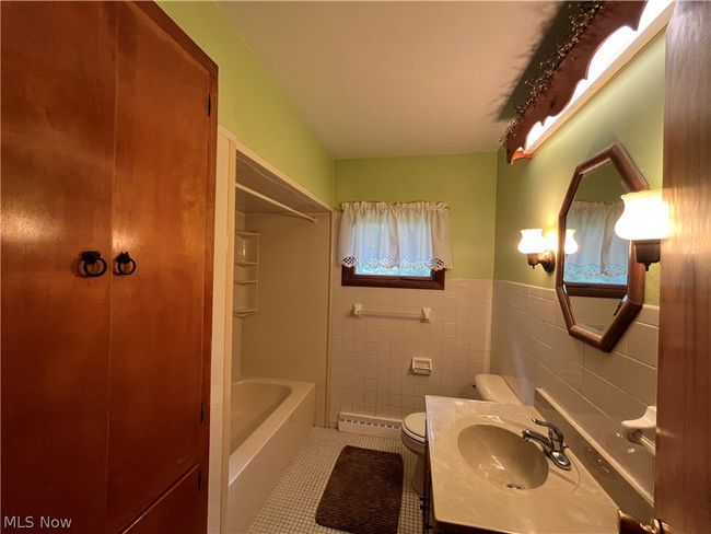 Full bathroom with tile walls, vanity with extensive cabinet space, toilet, tasteful backsplash, and tile flooring | Image 15