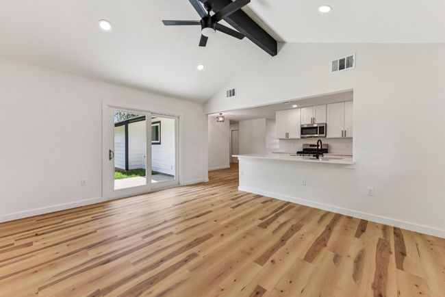 Unfurnished living room with beamed ceiling, light wood finished floors, recessed lighting, ceiling fan, and high vaulted ceiling | Image 18