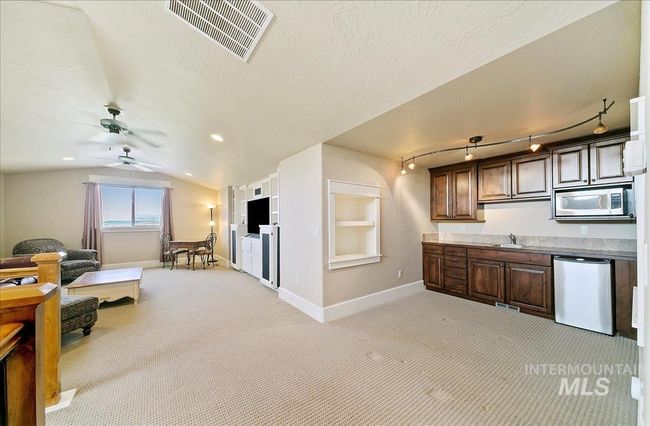 Kitchen featuring stainless steel appliances, open floor plan, light carpet, lofted ceiling, and a ceiling fan | Image 32