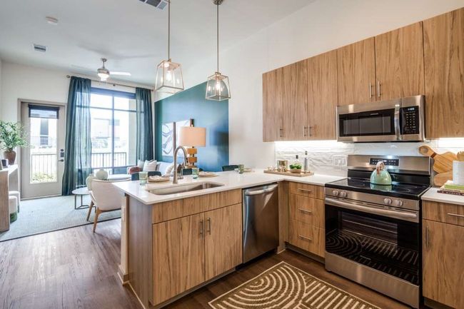 Kitchen featuring sink, appliances with stainless steel finishes, dark hardwood / wood-style floors, kitchen peninsula, and pendant lighting | Image 5