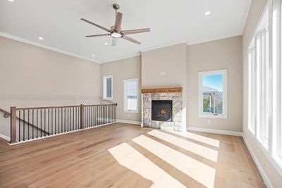 Unfurnished living room with a fireplace, light hardwood / wood-style floors, ceiling fan, and ornamental molding | Image 3