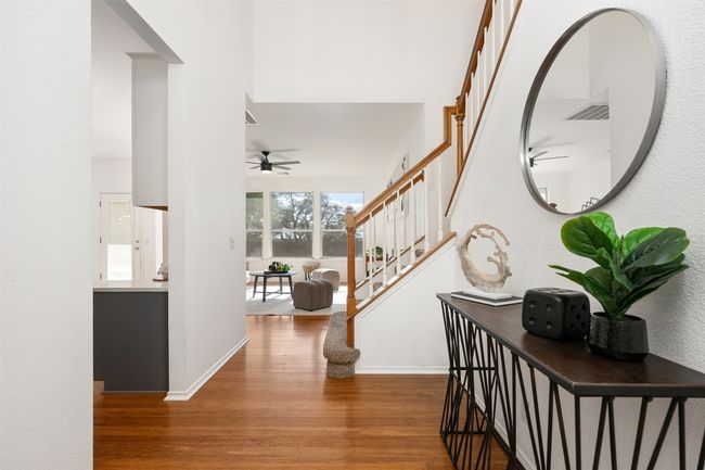 Foyer entrance featuring ceiling fan, visible vents, stairway, wood finished floors, and baseboards | Image 16