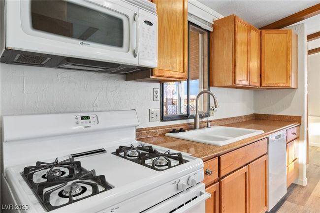 Kitchen featuring white appliances, a sink, and light wood style floors | Image 11