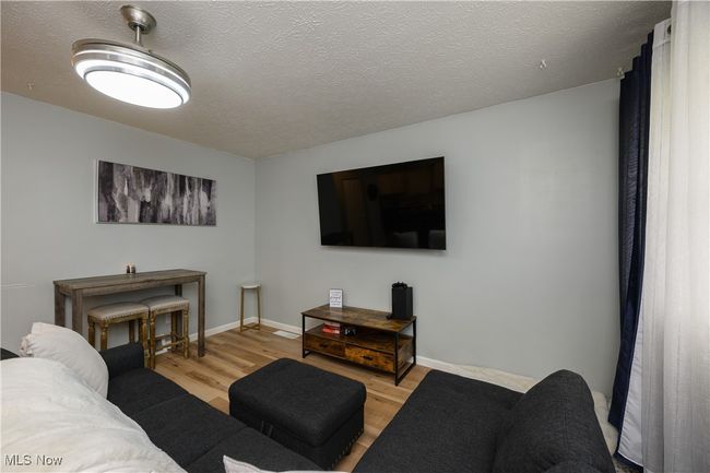 Living room with light wood-style floors and a textured ceiling | Image 5