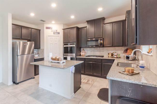 Kitchen with a sink, stainless steel appliances, dark brown cabinets, and visible vents | Image 6
