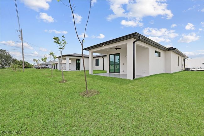 Back of property with stucco siding, a lawn, a ceiling fan, cooling unit, and a patio | Image 29
