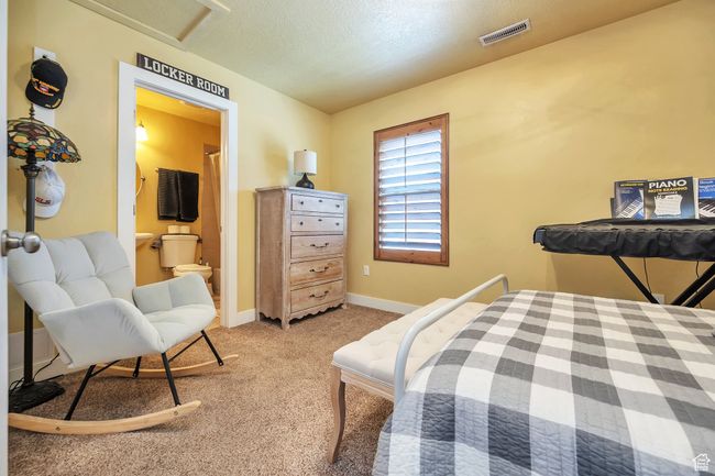Bedroom featuring ensuite bath, visible vents, baseboards, a textured ceiling, and light colored carpet | Image 18