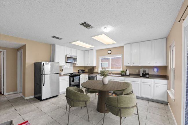 Kitchen featuring appliances with stainless steel finishes, a textured ceiling, white cabinets, and light tile patterned floors | Image 10