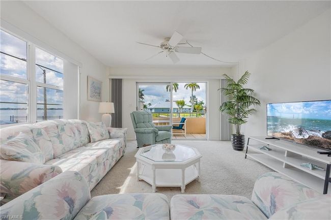 Carpeted living room with ceiling fan and a water view | Image 4