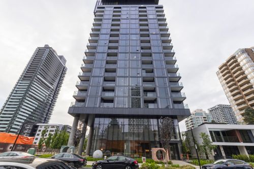 Modern high-rise with glass facade, individual balconies, and a ground-level commercial space | Card Image