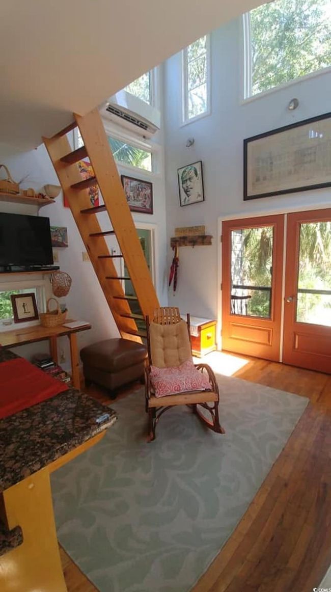 Living area with a towering ceiling, stairway, wood finished floors, an AC wall unit, and french doors | Image 13