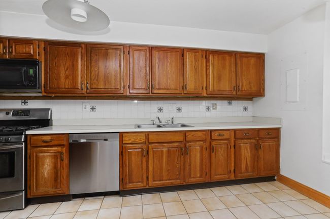 Kitchen with appliances with stainless steel finishes, a sink, light countertops, and decorative backsplash | Image 5