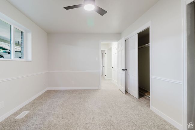 Unfurnished bedroom featuring a ceiling fan, a closet, visible vents, baseboards, and light carpet | Image 13