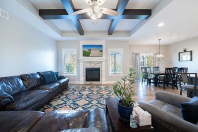 Living room featuring a stone fireplace, beam ceiling, hardwood / wood-style flooring, and plenty of natural light | Image 2