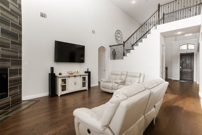 Living area with arched walkways, a towering ceiling, dark wood finished floors, baseboards, and visible vents | Image 8