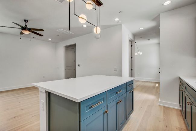 Kitchen with a ceiling fan, light wood finished floors, a kitchen island, recessed lighting, and baseboards | Image 14
