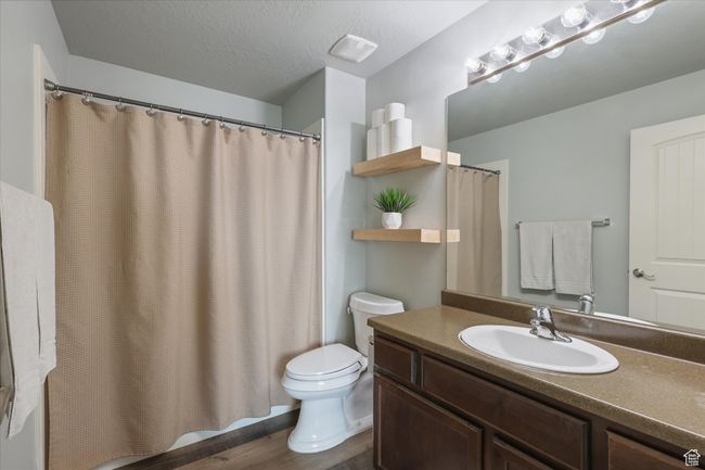 Full bathroom with wood finished floors, toilet, a textured ceiling, and vanity | Image 10