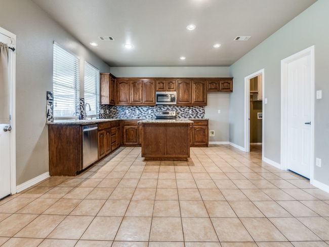 Kitchen featuring recessed lighting, decorative backsplash, appliances with stainless steel finishes, a kitchen island, and visible vents | Image 8