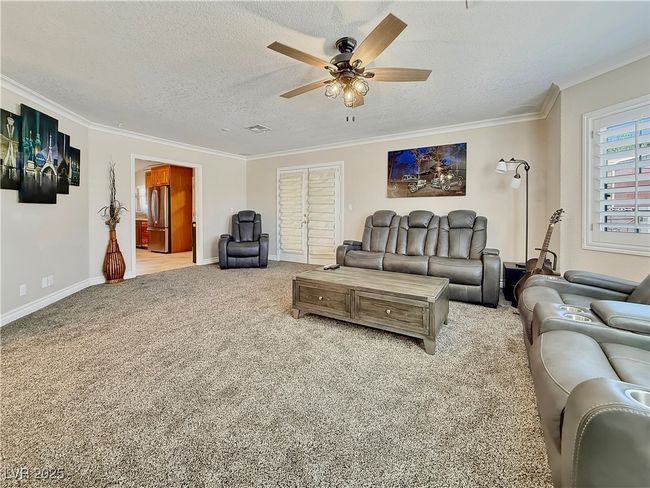 Living room featuring carpet flooring, a textured ceiling, crown molding, and ceiling fan | Image 18