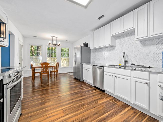 Kitchen with appliances with stainless steel finishes, tasteful backsplash, a chandelier, and dark wood-type flooring | Image 12