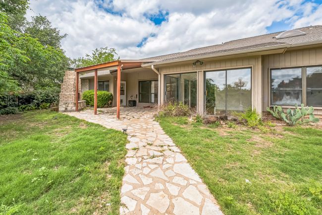 Rear view of house with a patio, a yard, and a shingled roof | Image 39