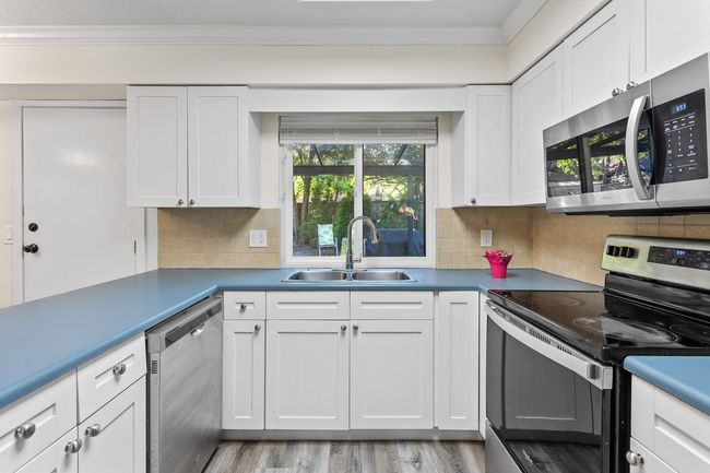 Kitchen featuring crown molding, a sink, white cabinets, and appliances with stainless steel finishes | Image 7