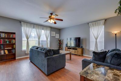 The living room features abundant natural light, luxury vinyl flooring, and attractive grey paint. | Image 3