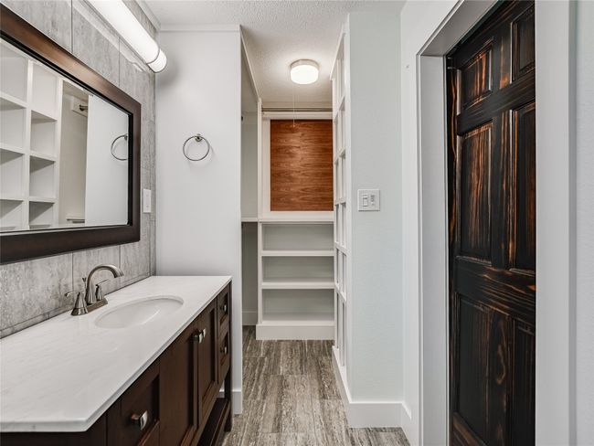 Bathroom featuring wood finished floors, vanity, a textured ceiling, decorative backsplash, and baseboards | Image 13
