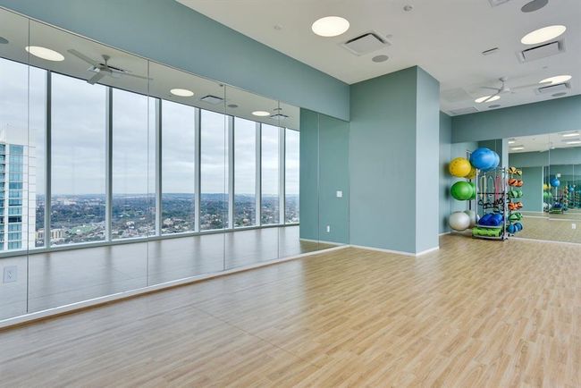 Exercise room with ceiling fan, wood finished floors, a towering ceiling, healthy amount of natural light, and baseboards | Image 23