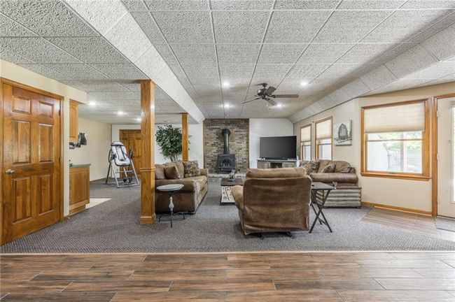 Living area with baseboards, a wood stove, recessed lighting, and wood finished floors | Image 57