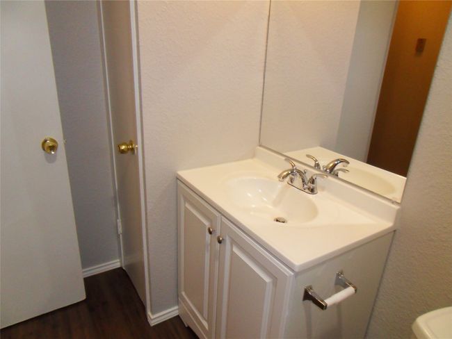 Half bathroom featuring vanity, wood finished floors, toilet, and a textured wall | Image 8