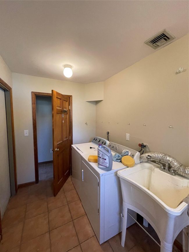 Laundry room with washer and clothes dryer, a sink, light tile patterned flooring, visible vents, and laundry area | Image 9