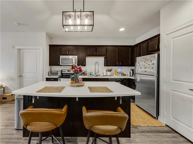 Kitchen with sink, a kitchen bar, a center island, stainless steel appliances, and light hardwood / wood-style flooring | Image 12