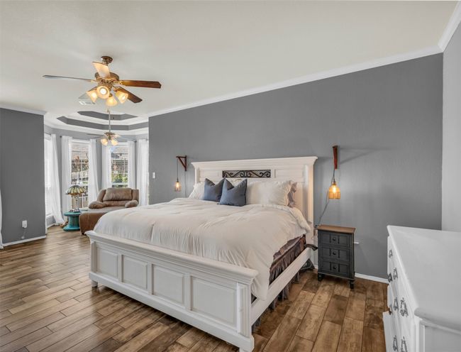 Bedroom featuring a raised ceiling, ceiling fan, crown molding, and dark wood-type flooring | Image 7