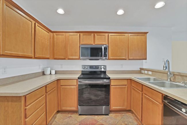 Kitchen with appliances with stainless steel finishes, light countertops, light stone finish flooring, and recessed lighting | Image 9