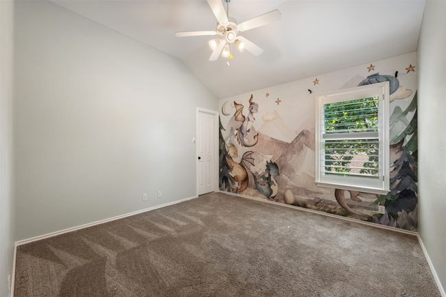 Bedroom with one wallpapered accent wall, a ceiling fan, and a walk-in closet. | Image 25